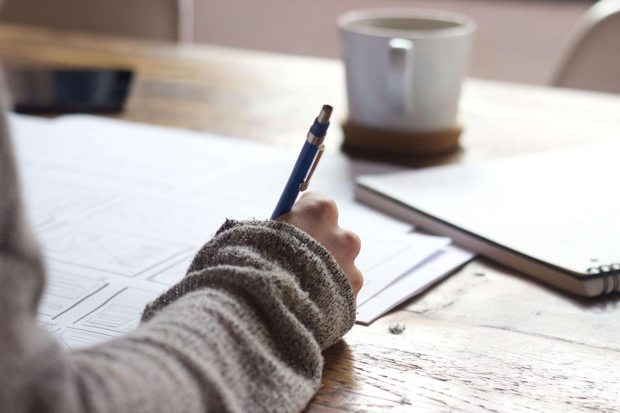 Person holding a pen and writing