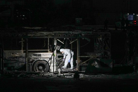 An Israeli police officer inspects the scene of one of a series of bus explosions in what authorities said appeared to be a militant attack in Bat Yam, central Israel, Thursday, Feb. 20, 2025. (AP Photo/Ohad Zwigenberg)