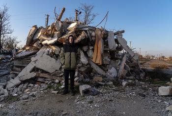 A teenage boy stands in front of a destroyed school in the village of Partyzanske close to the frontline.