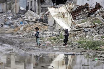 Two children walk through Gaza's destroyed landscape.