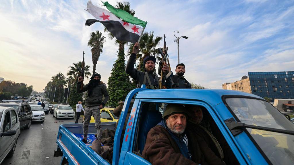 Syrian rebel fighters celebrate and hold up the Free Syria flag in Damascus after President Bashar al-Assad reportedly fled abroad (8 December 2024)