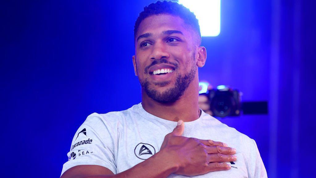 Anthony Joshua holds his hand to his heart and smiles