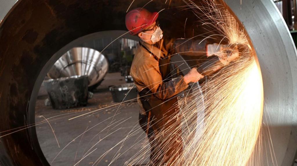 A worker polishes a piece of equipment in a factory which produces steel mining equipment for export in Jinhua, in China's eastern Zhejiang province on February 13, 2025. 