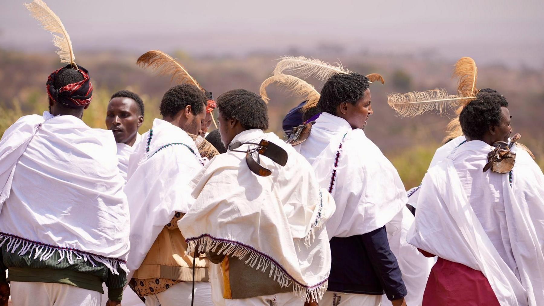 Young men wear ostrich feathers on their heads.