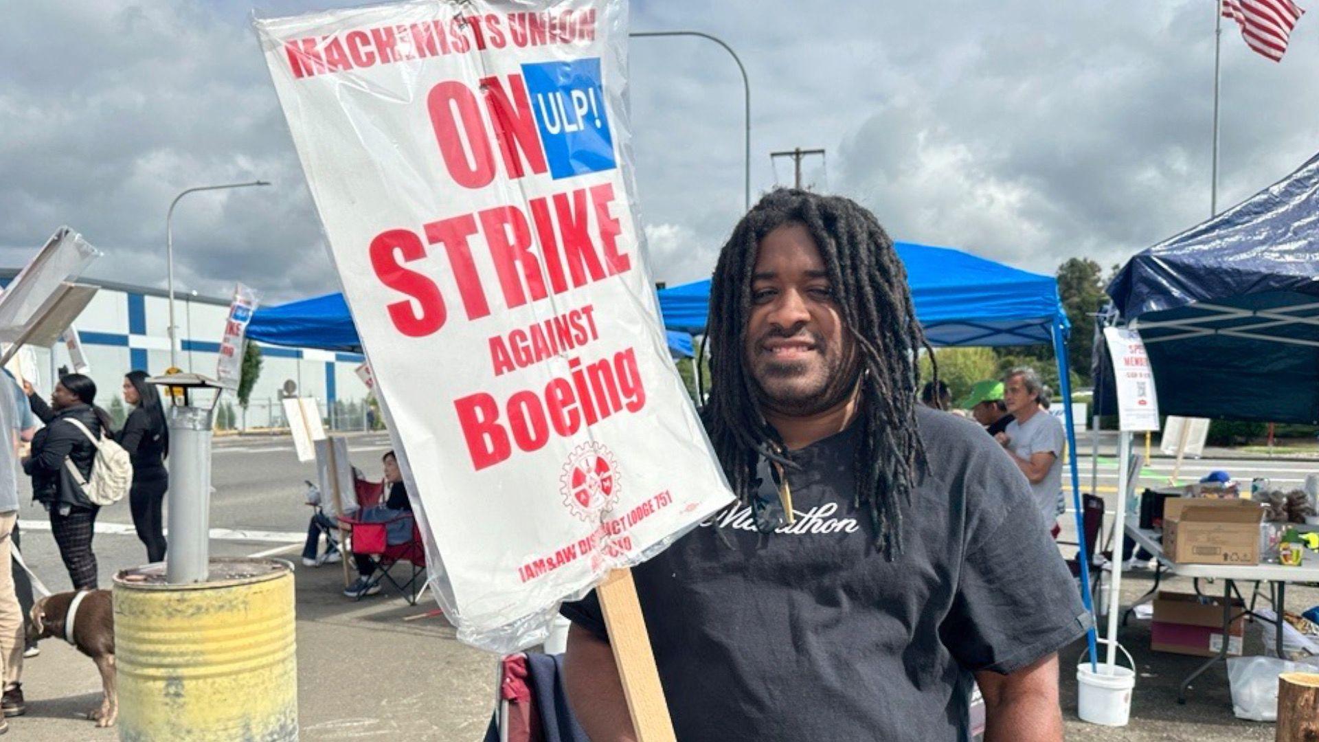 Davon Smith standing on the picket line, holding a sign saying "Machinists Union on strike against Boeing"