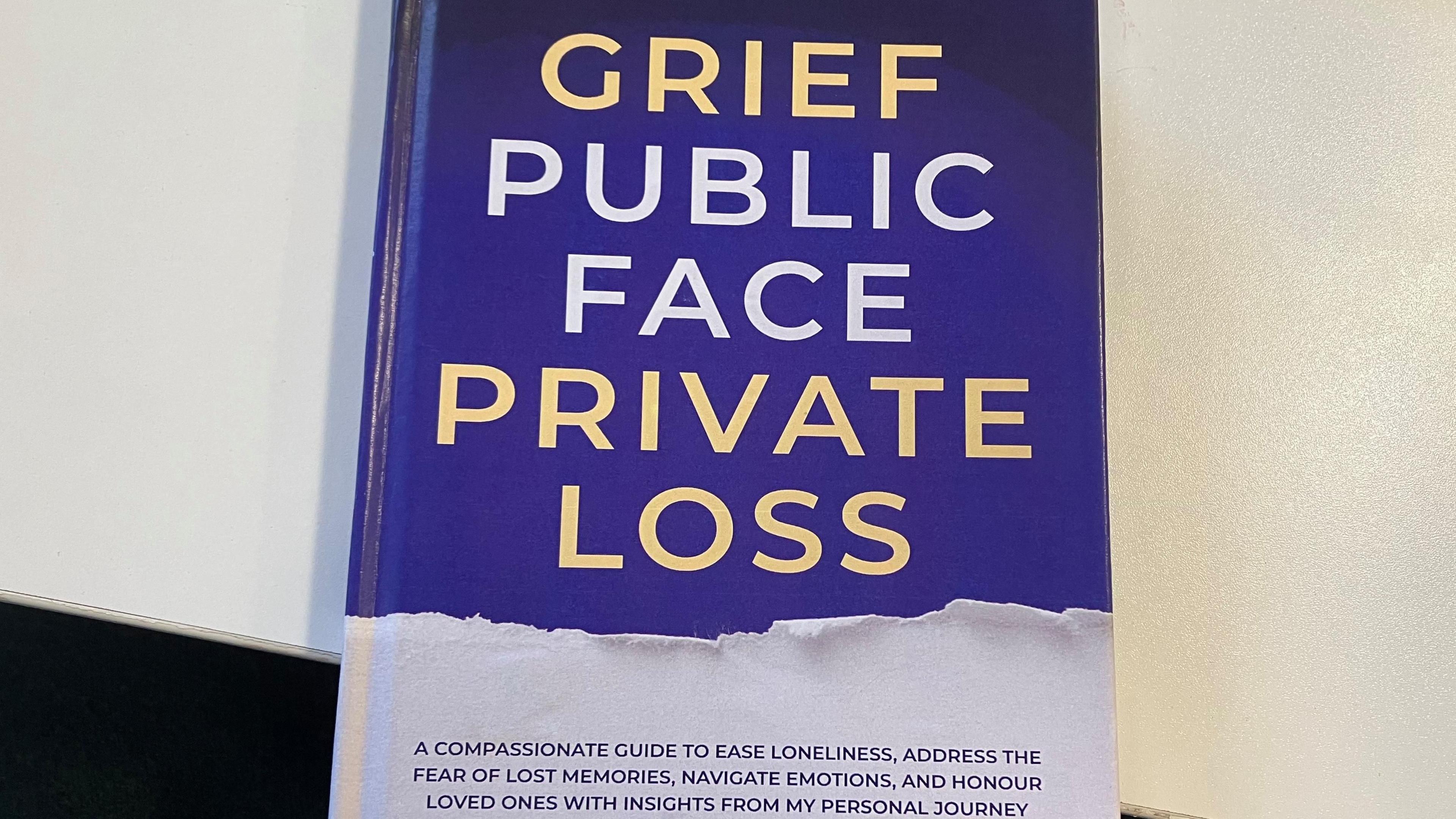 A navy book with gold and white font displaying the title: "Grief, Public Face, Private Loss"