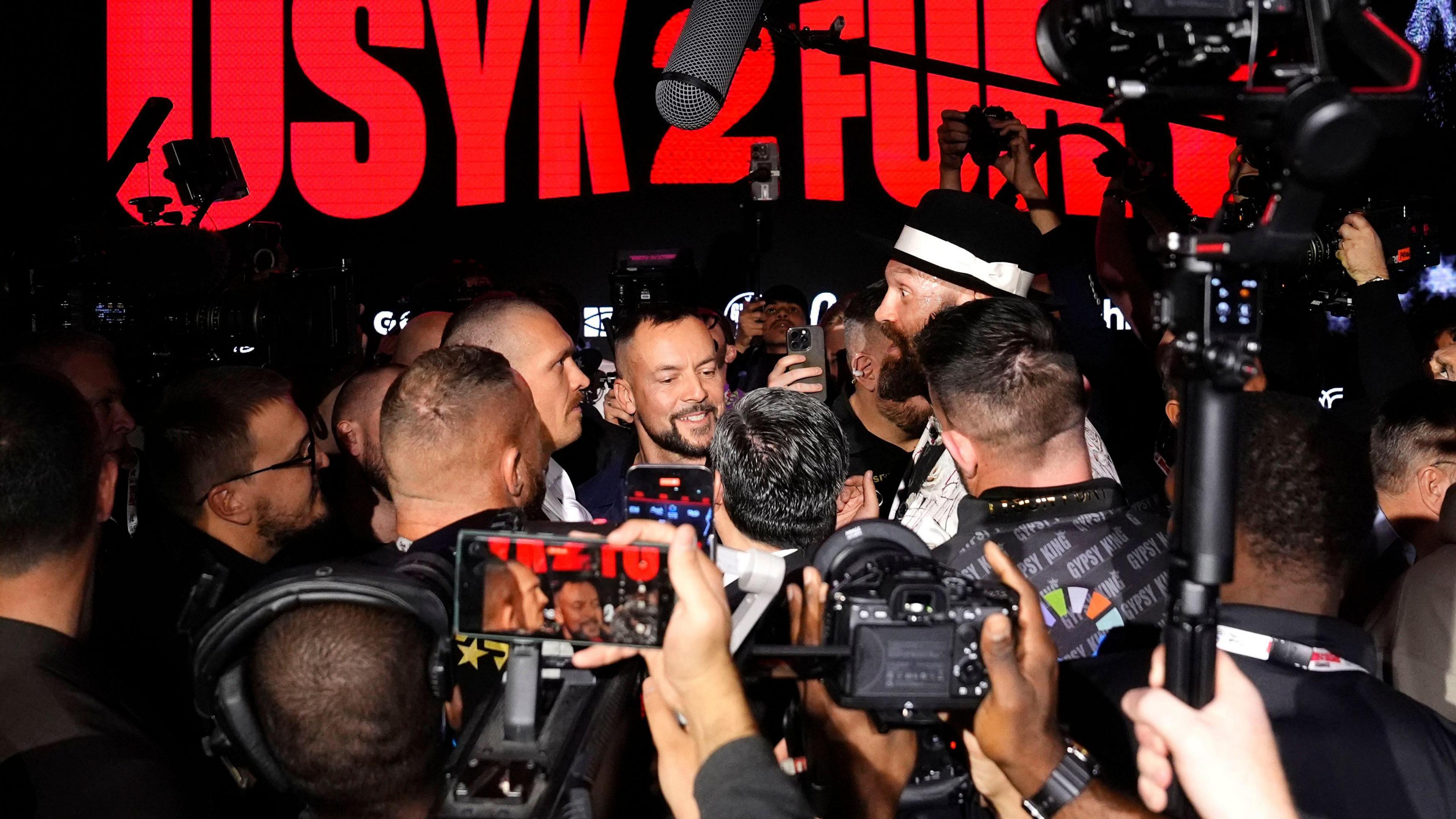 Oleksandr Usyk and Tyson Fury face-off among a crowd of people