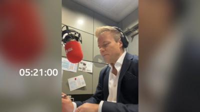 BBC weather presenter Simon King sits in front of a radio mic, preparing to read the shipping forecast 