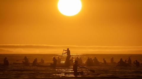 People paddle in the sea at Copacabana Beach