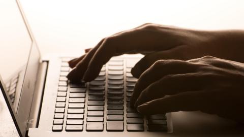 An open laptop with a person's hands on the keyboard.