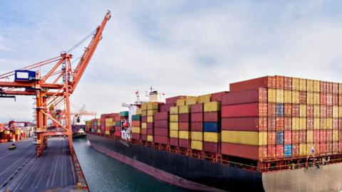 Aerial view of cargo ship with lots of containers on it, docked in a port.