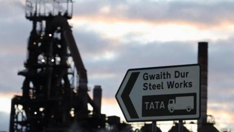 View of a road sign outside Tata Steel Port Talbot steel production plant at Port Talbot. The sign is in Welsh and English, in Welsh it says Gwaith Dur which is a translation of the English which reads Steel Works. Underneath there is the wording Tata with a picture of a truck