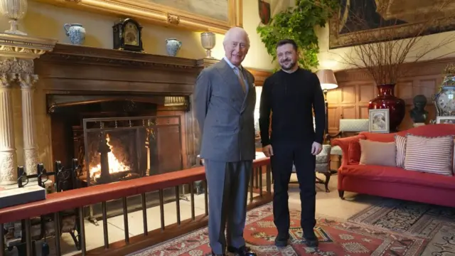 King Charles and Zelensky in grand room with fireplace.