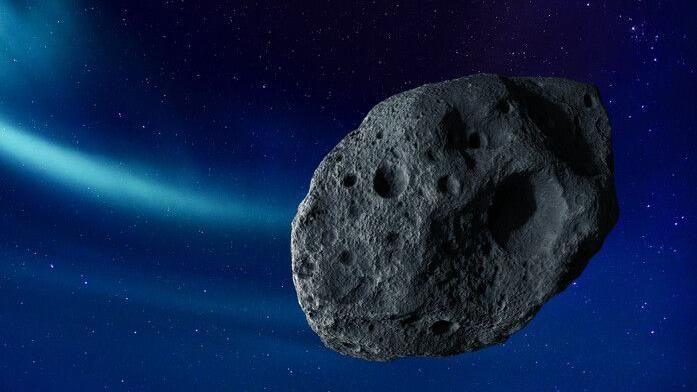 A rocky grey oval shaped asteroid stands out in space against the stars in an artist's mock up