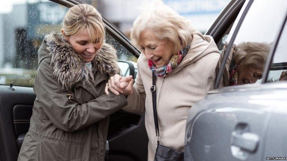 Young lady helping older woman out of a car