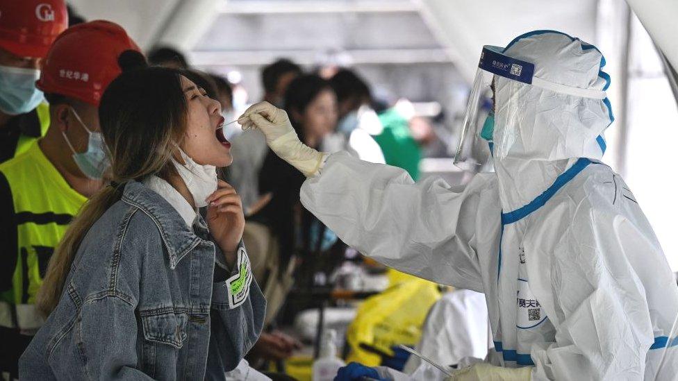 A health worker takes a Covid-19 swab sample from a woman in Beijing.