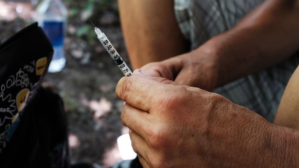 A drug user (face unseen) holds a needle - Pennsylvania, July 2017