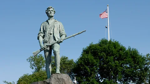 The Minuteman statue in Lexington, Massachusetts, with an American flag flying in the background (Credit: Alamy)