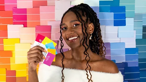 Micah Lumsden holding up colour swatches against a background of various bright colours