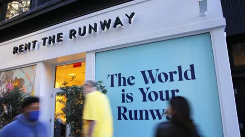 Michael M. Santiago via Getty Images Shoppers walk past a rent the runway store in New York