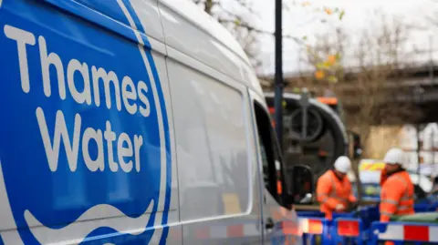 Reuters Thames Water employees carry out repair and maintenance in London. A van with Thames Water written down the side can be seen with two workmen in orange outfits further down the road.