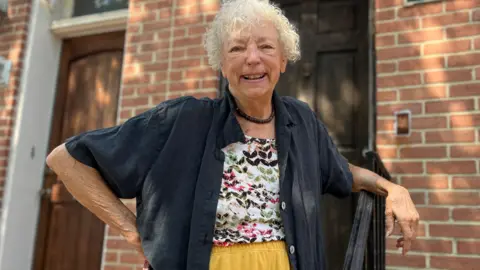 BBC Judy Aleksalza smiling outside of her home