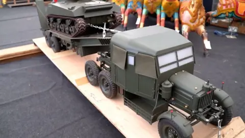 A green metal model of a World War Two-era tank transporter lorry with a Sherman Tank on its trailer.