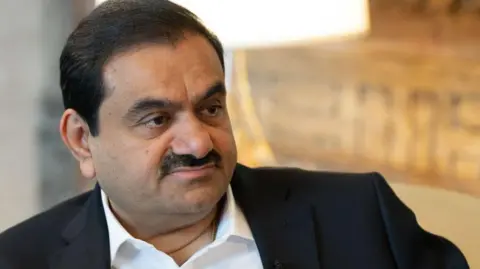 Getty Images A close-up of Gautam Adani's face  wearing a white shirt and black suit jacket during a 2024 interview with Bloomberg news