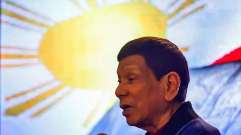 Former president of the Philippines Rodrigo Duterte delivers a speech with a Philippine flag in the background