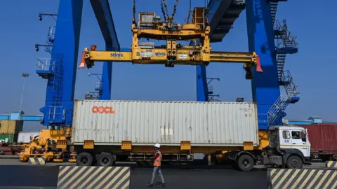 Getty Images A crane loads a cargo container on a truck inside the Mundra Port, India.