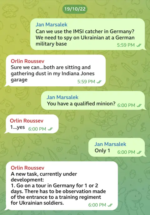 Telegram message exchange between Orlin Roussev and Jan Marsalek dated 19/10/22. JM asks: "Can we use the IMSI catcher in Germany? We need to spy on Ukrainian at a German military base". "Sure we can... both are sitting and gathering dust in my Indiana Jones garage," OR responds. "You have a qualified minion?" JM says. "1... yes," OR replies. "Only 1," JM writes. "A new task, currently under development: Go on a tour of Germany for 1 or 2 days. There has to be observation made of the entrance to a training regiment for Ukrainian soldiers," OR says.