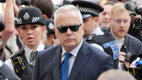 PA Media Huw Edwards surrounded by police outside court