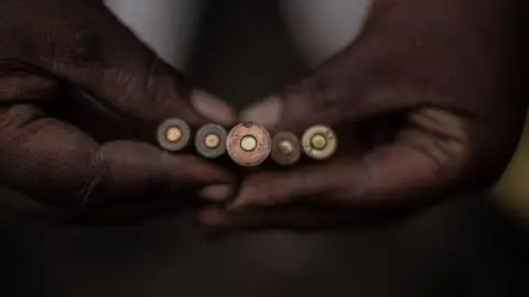 AFP A close up of a pair of hands holding five bullets.