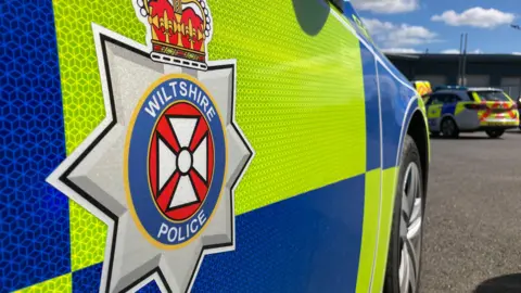 BBC Generic shot of the side of a Wiltshire Police car close-up, showing the logo