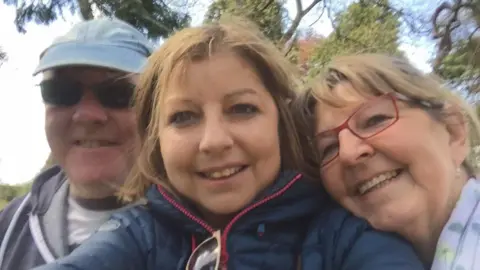 Nathan Angell Allison (centre) smiles at the camera with her mum Helen (right) and father David (left) 