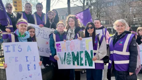 A group of women hold placards to celebrate International Women's Day