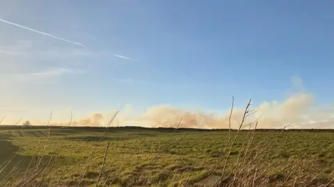 Charles Heslett/BBC Moorland with smoke on the horizon