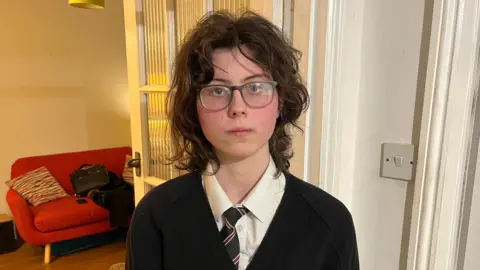 Qays Najm/BBC Portrait photograph of Martha, a 16-year-old girl, with a neutral expression and wearing her Reepham High School uniform. 