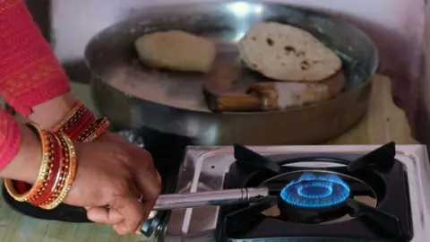 Getty Images A woman lights a stove connected to an Indian Oil Corp. Indane brand liquefied petroleum gas (LPG) cylinder at a village home in Greater Noida, Uttar Pradesh, India, on Monday, Feb. 22, 2021. Photographer: T. Narayan/Bloomberg via Getty Images