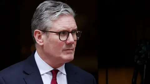 EPA British Prime Minister Keir Starmer wearing a suit and red tie looks sternly out of the door to 10 Downing Street