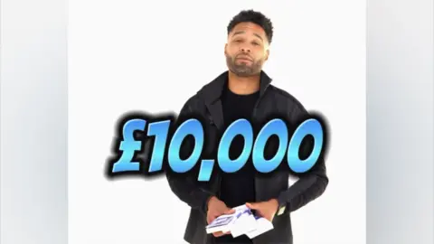 Instagram Mr Hall, who has short, cropped dark hair and short shaved facial hair. He is wearing a black jacket with grey jeans and holding money. A piece a text stretching across the screen says £10,000 in advert of a competition