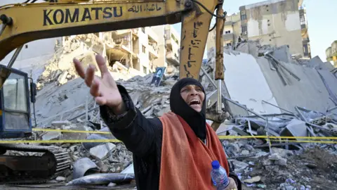 A woman reacts after an Israeli air strike destroyed a multi-storey building in the southern Beirut suburb of Chiyah (21 October 2024)