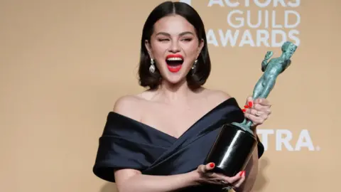 Actress Selena Gomez smiles as she holds a SAG award trophy