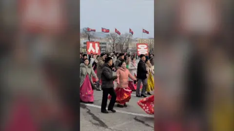 North Koreans dancing outside.