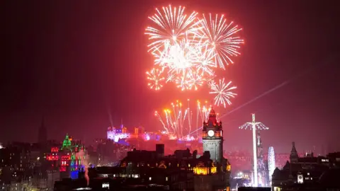 PA Media Hogmanay celebrations in Edinburgh. Firework displays can be seen behind Edinburgh Castle.