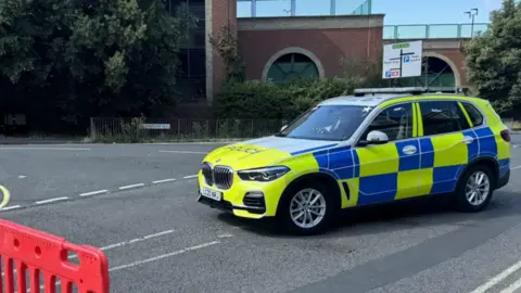 George King/BBC An officer and two police cars at the cordon in Ipswich
