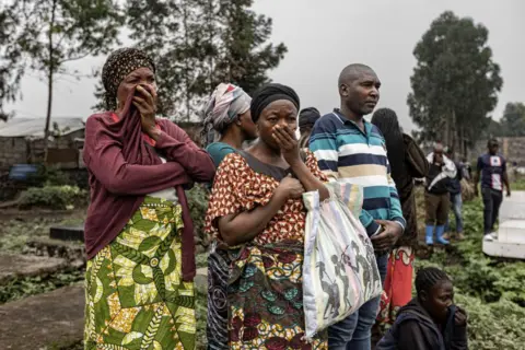 AFP Two women cover their mouths as their friends and relatives are buried following the capture of Goma by M23 rebels