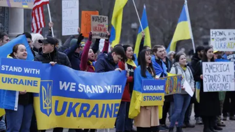 EPA-EFE/REX/Shutterstock Protesters holding Ukraine flags and pro-Ukraine signs with the words "We Stand With Ukraine", "Ukraine Strong" and "America Stands With Ukraine"