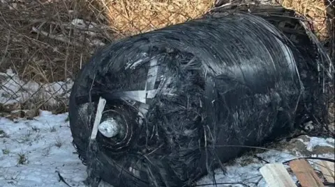 Adam Borucki A charred cylindrical tank measuring around1.5 metre by 1 metre on the snowy ground next to a wire fence on the property of Adam Borucki. 