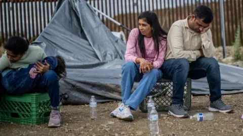 Migrants seeking asylum from Gujarat, India wait to be apprehended by U.S. Customs and Border protection officers after crossing over into the U.S. on June 25, 2024 in Ruby, Arizona.